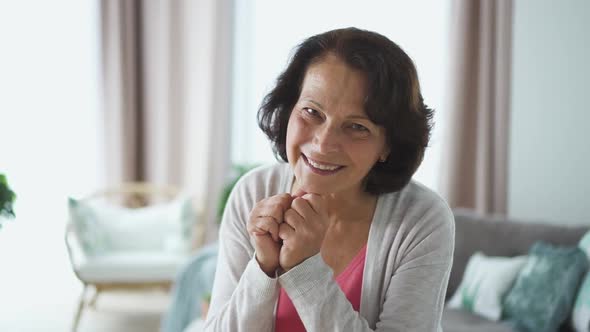 Happy Mature Businesswoman Is Posing for Portrait Sitting in Apartment Room