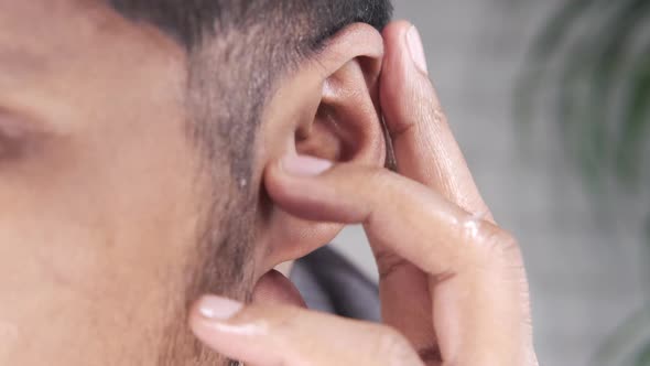 Close Up of Young Man Holding Ear Suffering Pain