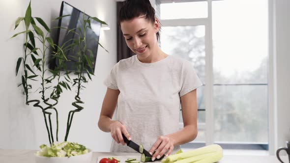 A beautiful woman cutting vegetables cooking salad at the kitchen