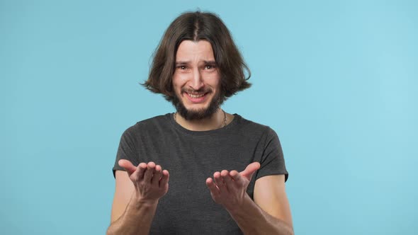 Portrait of Caucasian Man Looking at Camera Expressing Misunderstanding with Throwing Up Hands and