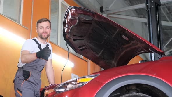 An Employee of a Professional Mechanical Car Service Looks Under the Hood of the Car