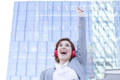 Joyful young woman in suit listening to music with headphones in city - PhotoDune Item for Sale