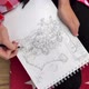 A young girl sits on the floor and draws anime in an album with a simple pencil - VideoHive Item for Sale