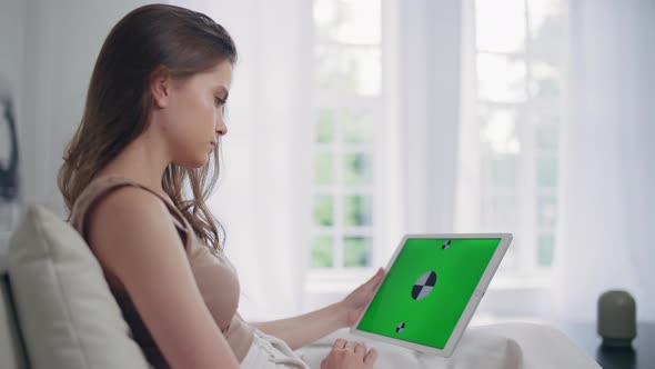 Young Girl at Home in the Living Room with a Tablet with Green Screen