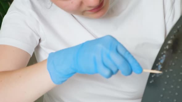 A Woman Cleans the Sole of an Iron From Carbon Deposits with an Orange Stick