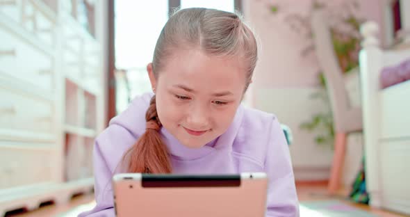 Teen Girl Smiles While Types on the Tablet