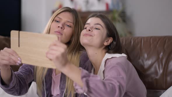 Two Cute Young Women Fighting for Hand Mirror at Pajama Party Indoors