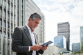 A businessman using his digital tablet outside the office building - PhotoDune Item for Sale