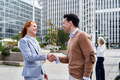 A business woman and a businessman shaking hands outside the work building - PhotoDune Item for Sale