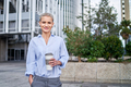 office worker standing outside office buildings holding reusable cup of coffee looking at camera - PhotoDune Item for Sale