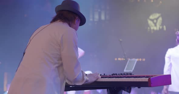 A Young Man Plays a Synthesizer on Stage