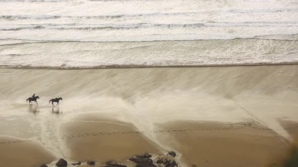 Aerial view of people riding horses at gallop on the beach