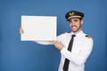 Smiling young pilot pointing at blank sign on blue background - PhotoDune Item for Sale