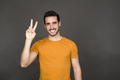 Young man with victory sign in studio portrait - PhotoDune Item for Sale