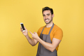 Smiling young man pointing at phone on yellow background - PhotoDune Item for Sale