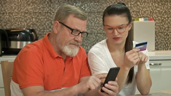 Beautiful Young Woman Is Explaining To Her Elderly Father How To Shop Online