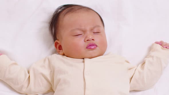 Top view happy newborn baby lying and sleep on a white bed and blanket comfortable