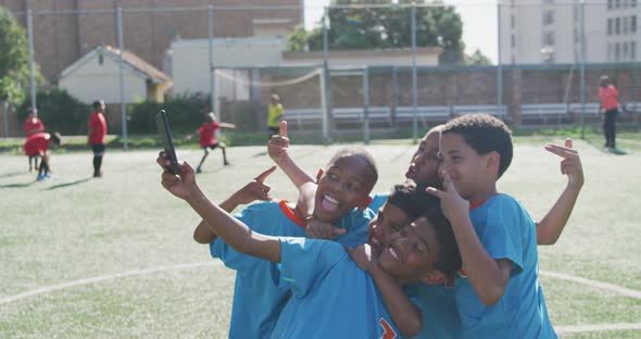 Soccer kids in blue taking a selfie and laughing in a sunny day