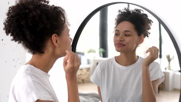 Joyful Beautiful Happy African American Girl in a White Basic Tshirt Stands in Front of a Mirror in