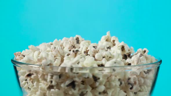 Rotating Glass Bowl with Fresh Popcorn on Blue Background