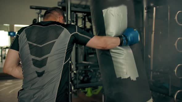 Strong Sporty Athlete Hitting Punching Bag Indoor of Gym