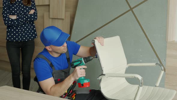 Handyman Repairs a Chair in the Living Room