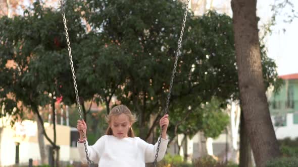 Happy Girl, Having Fun On Swing In Park at Sunset.