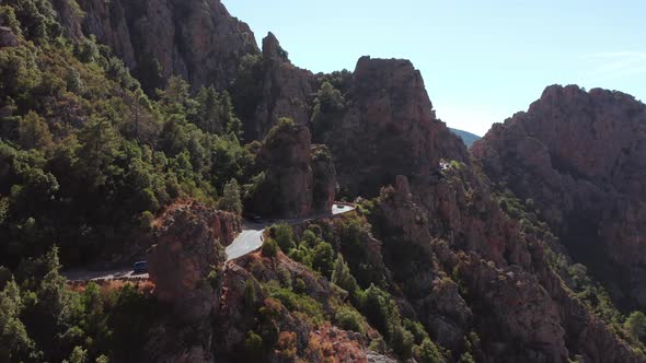 Panoramic Aerial View of Rocky Red Mountain Canyon with Electric Car Driving in a Curved Road in a