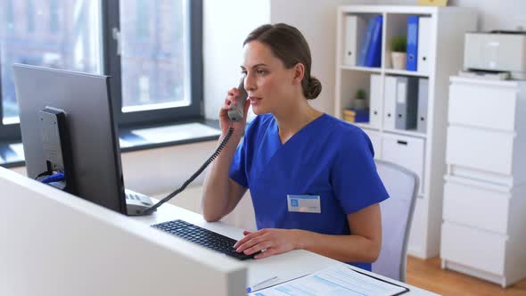 Doctor with Computer Calling on Phone at Hospital