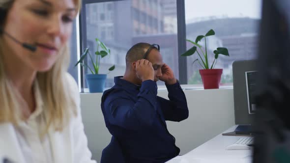 Diverse business people sitting using computers talking with phone headsets