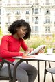 Young afro woman using tablet while drinking coffee on terrace - PhotoDune Item for Sale