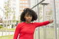 Serious young afro girl leaning on fence looking at camera. - PhotoDune Item for Sale