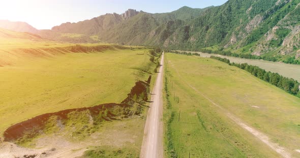 Aerial Rural Mountain Road and Meadow at Sunny Summer Morning. Asphalt Highway and River.