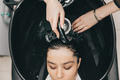 The hairdresser washes the head of a girl in a barbershop. brunette came for a haircut - PhotoDune Item for Sale