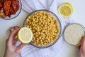 Cropped shot of woman, ingredients for hummus in bowl, sun-dried tomatoes, lemon, garlic, sesame - PhotoDune Item for Sale