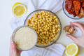Cropped shot of woman, ingredients for hummus in bowl, sun-dried tomatoes, lemon, garlic, sesame - PhotoDune Item for Sale