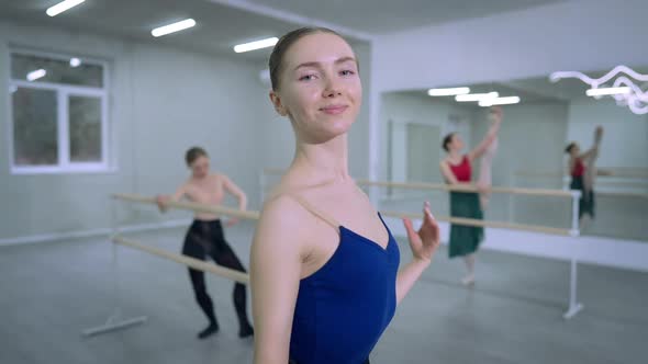 Medium Shot of Confident Charming Slim Ballerina Looking at Camera Smiling with Ballet Dancers
