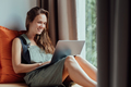 College female student uses a computer while sitting on a windowsill in a hostel - PhotoDune Item for Sale