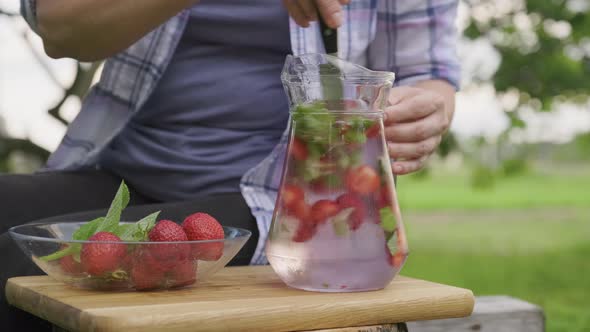 Close Up of Female Hands Making Natural Drink with Strawberries and Mint