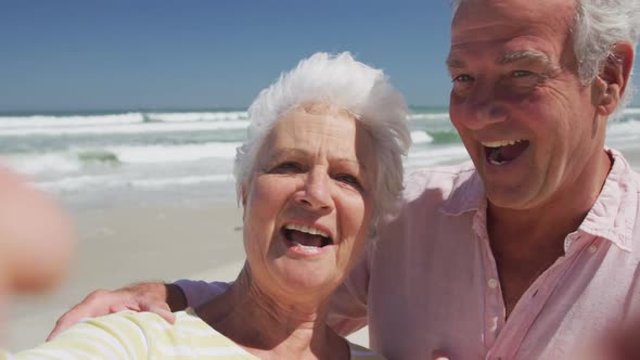 Portrait of happy senior caucasian couple blowing kisses looking at camera on the beach