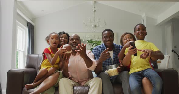 Happy african american family cheering while watching match in tv