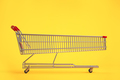 Long shopping cart on yellow background. Sales an discounts concept. - PhotoDune Item for Sale