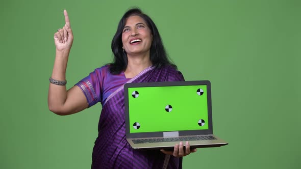 Mature Happy Beautiful Indian Woman Thinking While Showing Laptop and Pointing Up