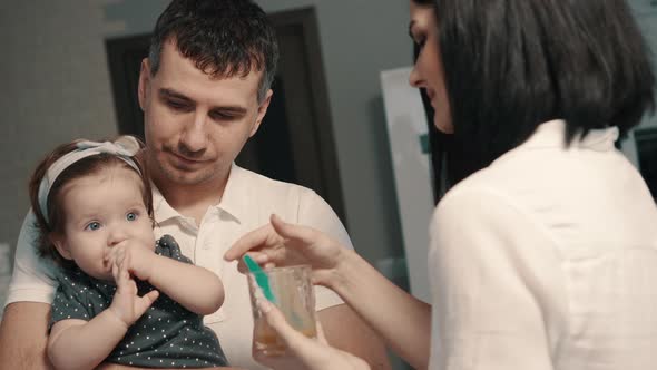 Young Parents Feed Baby Daughter at Home