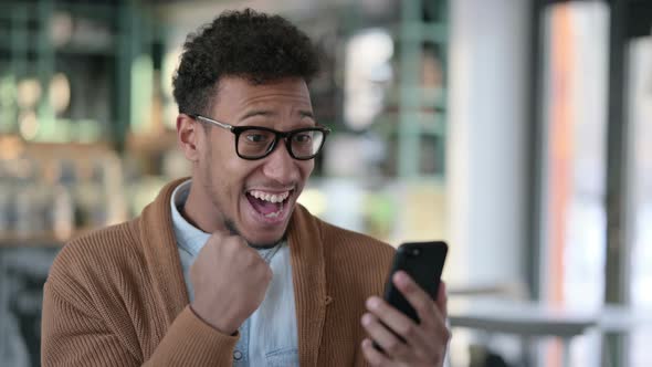 Young African Man Celebrating Success Smartphone