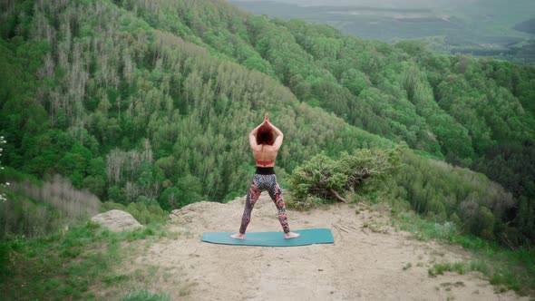 Athletic Woman Practices Yoga on Top Mountain