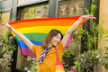 Happy LGBTQ+ youth with pride flag in street - PhotoDune Item for Sale