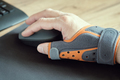 Male hand with a thumb brace. Fixing orthosis.  Working with a computer mouse. - PhotoDune Item for Sale