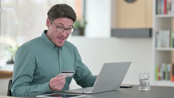 Middle Aged Man Excited By Online Shopping Success on Laptop