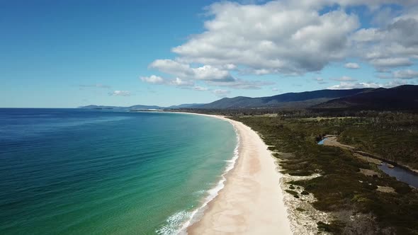 Drone PAN DOWN Over White Sand Beach and Blue Ocean Waves In Tasmania, Australia